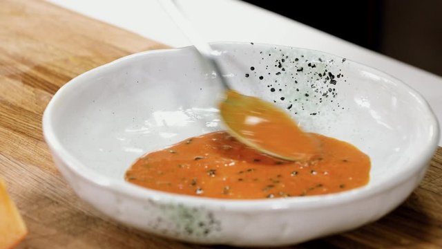 Close up of man putting a sea buckthorn sauce onto the plate with spoon. 4K