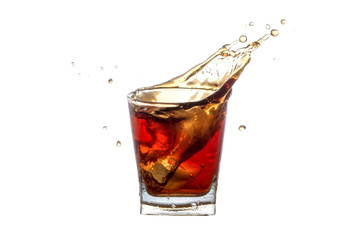 Splash pop soda in glass close-up isolated on a white background. Splashing in a glass with soda from falling ice cubes isolated on a white background.