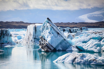 Icebergs floating. Ices and volcanic ash. Glacier lagoon. Melting ice. South coast Iceland.Volcanic ash on the arctic ice. Ice age glacier crevasse melting fast. Global warming. The edge of a glacier