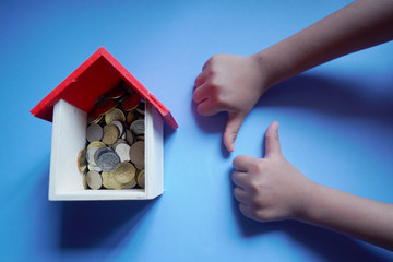 A replica house with a coins and a hand. Conceptual moratorium package as financial assistance...