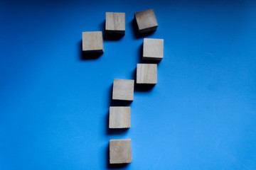 A wooden block forming a question on a blu background