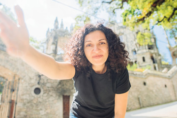 Young woman tourist in black t-shirt taking a selfie in front of a castle Quinta da Regaleira in Sintra. Concept of the beginning of tourism in Portugal.