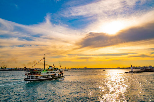 Famous ferries, VAPUR, in Istanbul is taking off from kadikoy port during sunset with colorful sky background. Panoramic view of the Bosporus 