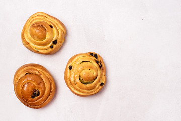 Three Freshly Baked Buns with Raisins and Cinnamon on Light Gray Background Top View Sweet Homemade Pastry Swedish Dessert Copy Space