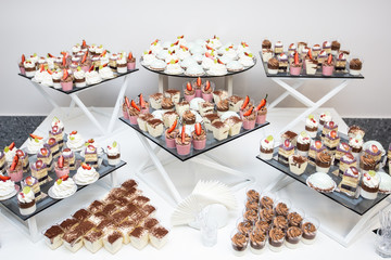 Table with sweets, buffet with cupcakes, candies. Candy bar, a table with sweets and desserts. Buffet with delicious cupcakes, cake pops, biscuits. Wedding, birthday and surprise concept.