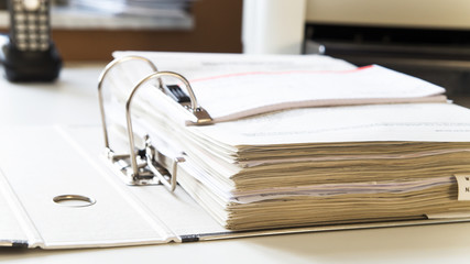 File folder with tax documents for tax office on desk with telephone and printer in the background