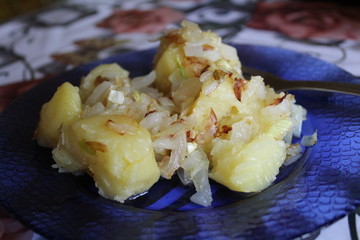 boiled potatoes with fried onions on a blue plate, home-made food