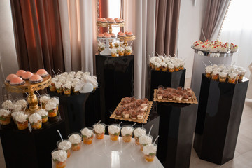 Table with sweets, buffet with cupcakes, candies. Candy bar, a table with sweets and desserts. Buffet with delicious cupcakes, cake pops, biscuits. Wedding, birthday and surprise concept.