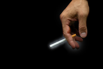 close up man's hand is holding a cigarette that has not yet been lit on a black background, the World No Tobacco Day concept.