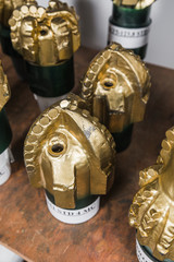Golden color rock Drill Bits on shelving in stock. Oil drilling equipment for drilling rig operation on oil platform in oil and gas industry. Brand new PDC Polycrystalline Diamond Compact drilling bit