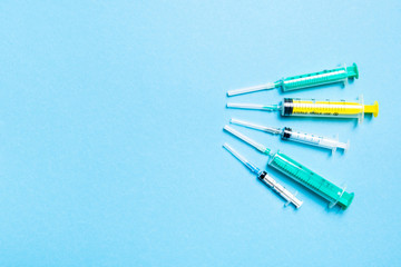 Top view of medical syringes with needles at blue background with copy space. Injection treatment concept