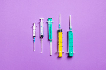 Top view of medical syringes with needles at purple background with copy space. Injection treatment concept