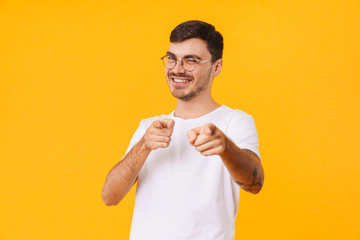 Photo of joyful young man pointing fingers at camera and winking