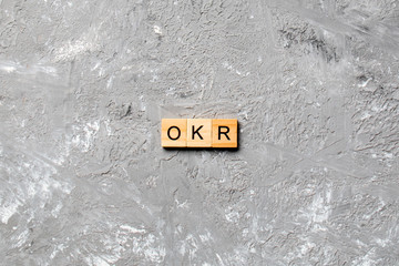 OKR word written on wood block. abbreviation of Objective Key Results text on cement table for your...