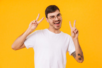 Photo of joyful young man gesturing peace sign and smiling