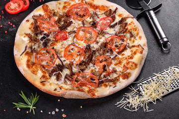Fresh hot pizza with meat, mushrooms, cheese and tomatoes made in an oven