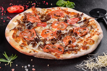 Fresh hot pizza with meat, mushrooms, cheese and tomatoes made in an oven