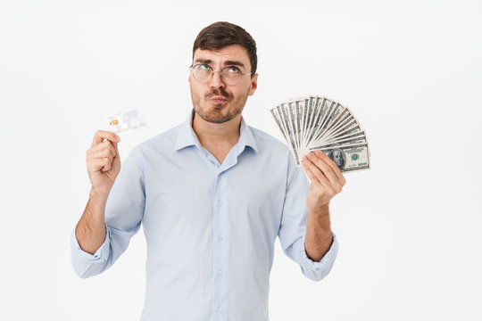 Photo of confused young man holding dollars and credit card