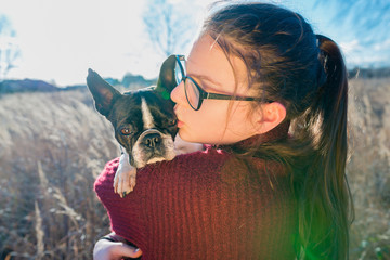 Portrait of girl hugging a puppy boston terrier dog on nature background