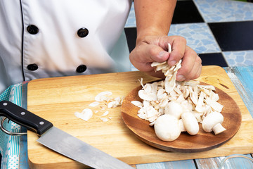 Chef putting slice of mushrooms to the plate