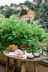 Tea ceremony, pouring tea from a teapot into a tea cup on a background of beautiful nature, fresh cherry and croissant. Hot cup of tea on rustic table. 
