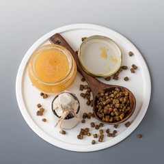 Beekeeping products. Propolis, bee pollen and a jar of fresh honey on a gray background with copy space. Selective focus.