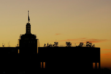 Silhouette of a flag and telecommunications antennas on the top of a skyscraper in downtown Sao Paulo, Brazil.