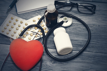 A heart with a stethoscope lies on a wooden background. Healthy heart