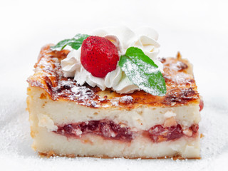 A piece of cake with fruit filling decorated with strawberries and mint leaves on a white background