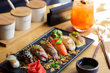 Nigiri sushi with salmon, eel, tuna and prawn, served on transparent plate. Delicious traditional Japanese food, tasty seafood, restaurant concept, food background.