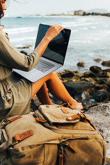 Young pretty female freelancer working on a laptop, remote work concept. Work by the sea. Using...