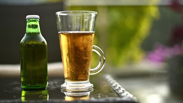 Fresh beer poured into glass on garden table overlooking garden scenery in a shallow depth of field ,blurred background.