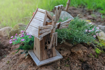An example of landscape design with Alpine hill, stones, wooden mill for a home garden  plot in a garden shop in the open air. © Александра Замулина