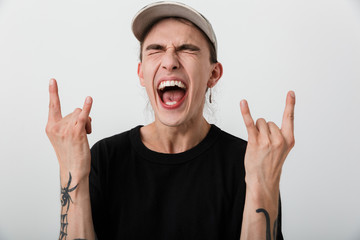 Portrait of excited young man wearing black clothes showing fingers as horns and screaming