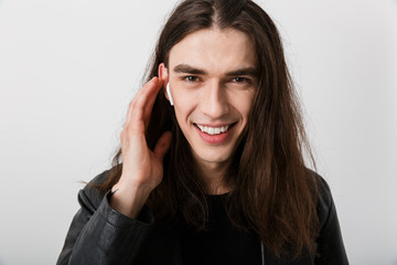 Portrait of brunette happy man with long hair wearing lather jacket smiling and listening music...