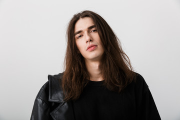 Portrait of handsome young man with long hair wearing black lather jacket posing and looking at...