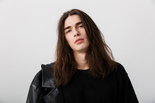 Portrait of handsome young man with long hair wearing black lather jacket posing and looking at camera