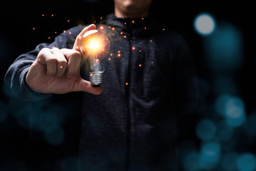 Businessman holding glowing lightbulb with orange light . Creative new business idea concept.