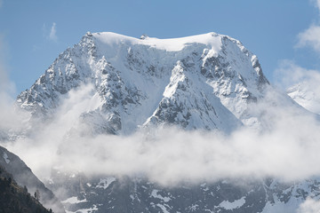 Peak of the mountains in the clouds on a background of blue sky.