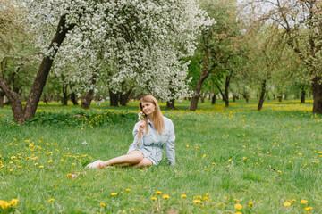 Girl in a flowering garden. A young blond woman is walking in a park. Portrait of a beautiful girl in the park.