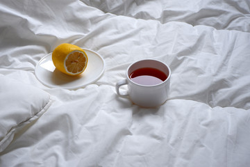 A Cup of tea and half a lemon on a white blanket. Background. Minimalism