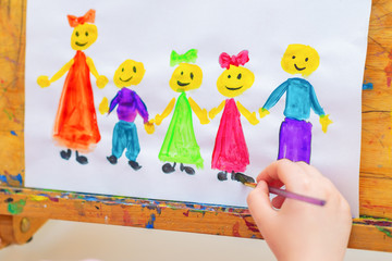 Little girl is drawing the children with words Children's Day on a wooden easel for the holiday Happy Children's Day.