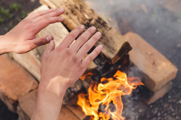 Human hands near the orange warm flame. Spring barbeque preparation. A lot of smoke. Orange bricks and firewoods. Time for rest