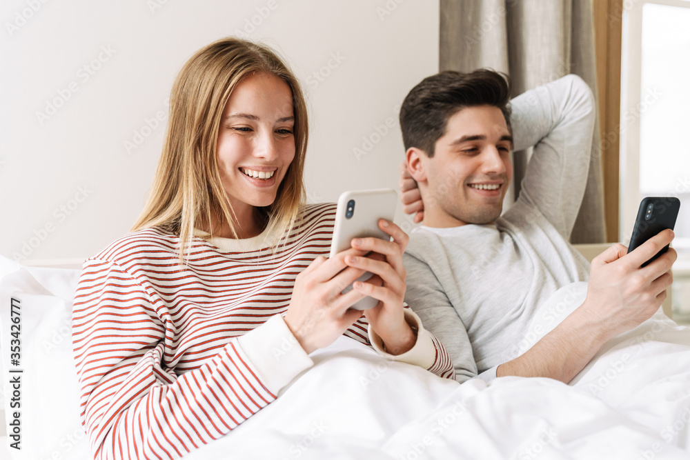 Sticker portrait of happy couple smiling and using smartphones while lying