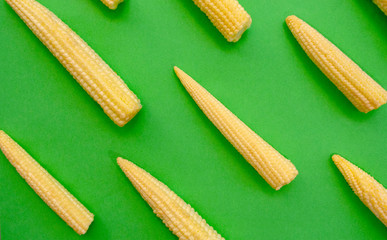 Baby corn pattern on green background. Top view. Yellow baby corn flat lay.