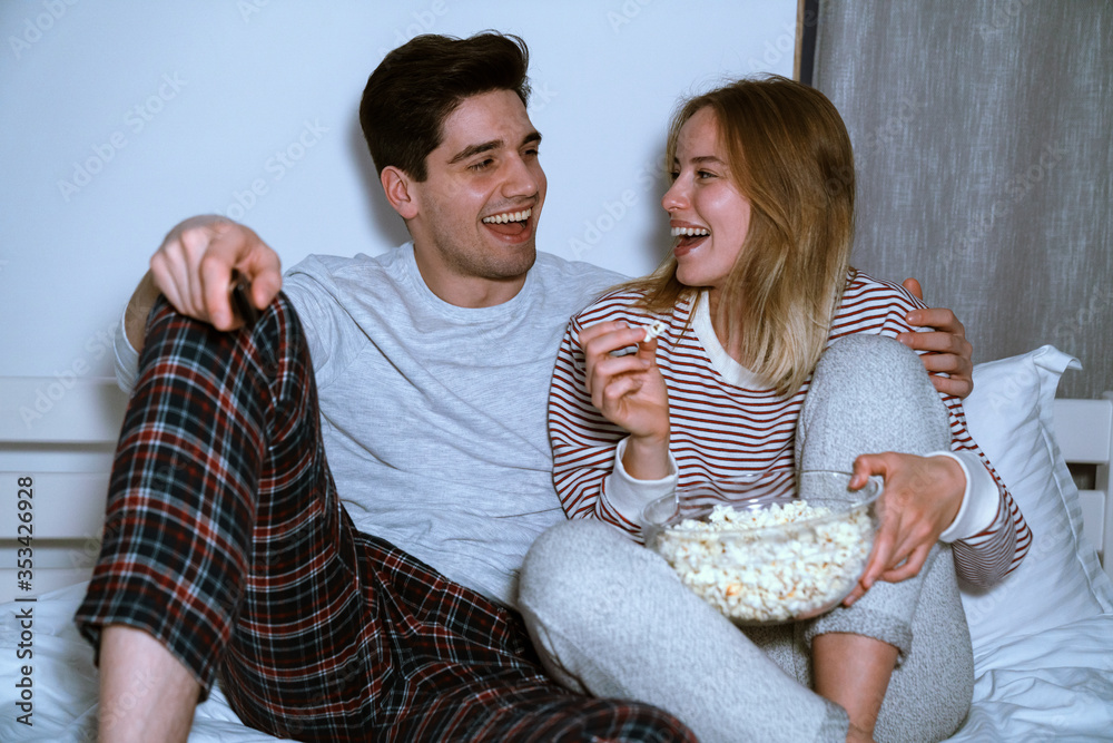 Canvas Prints portrait of laughing caucasian couple watching tv and eating popcorn