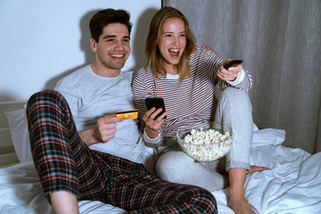 Portrait of couple using cellphone and holding card while watching tv