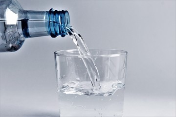 Drinking water pouring water from plastic bottle to the glass. photo isolate on white front view copy space 