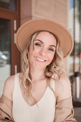 A young woman in a hat is smiling. Summer city portrait.