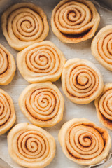 Obraz na płótnie Canvas Delicious homemade raw cinnamon rolls bun dough in rectangle shaped baking tray on the white baking paper. Top view. Interesting pattern
